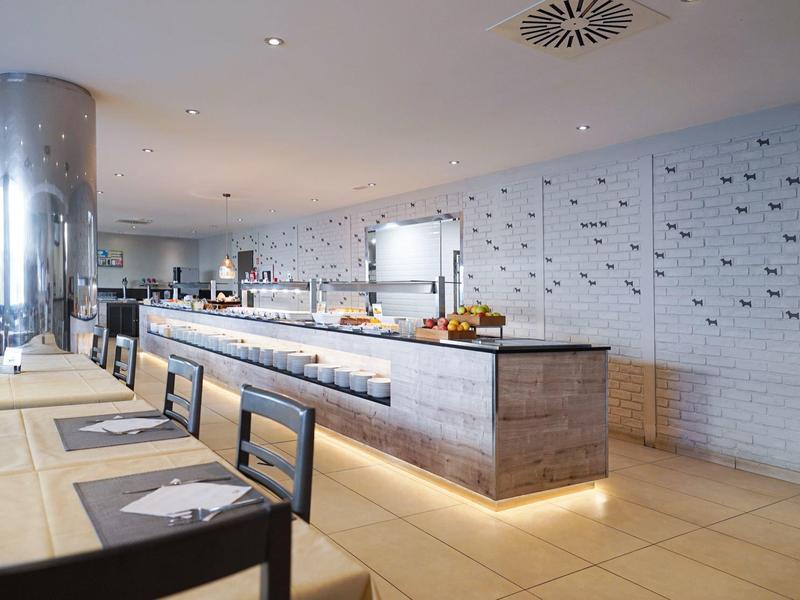 Modern restaurant met lang buffet en gedekte tafels in lichte omgeving.