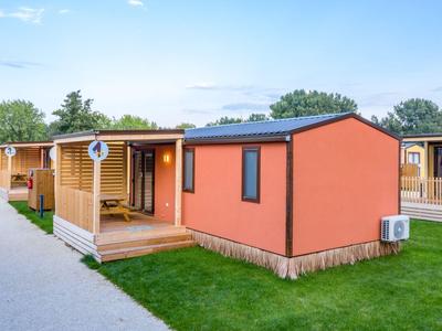 Ein modernes, oranges Gartenhaus mit Terrasse in einer Hotelanlage bei Tageslicht.