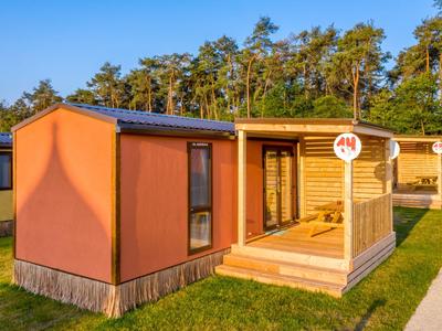 Moderne Holzhäuser mit Veranda auf Grünfläche bei klarem Wetter, ideal für Urlaub.