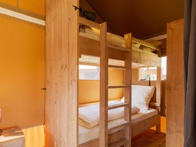 Holz-Etagenbett in einem warm beleuchteten Raum mit orangenen Wänden und Holzboden.