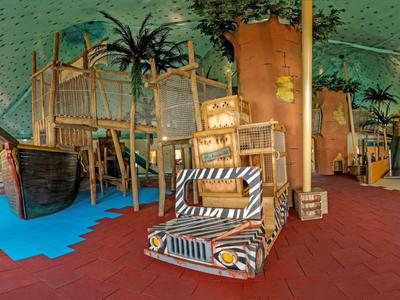 Innenbereich eines Hotels mit kindgerechtem Spielplatz aus Holz und farbigem Bodenbelag.
