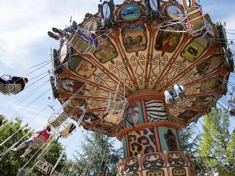Weißes Safari-Fahrzeug mit Zebramuster, darauf steht ein Kind und beobachtet einen Leoparden.
