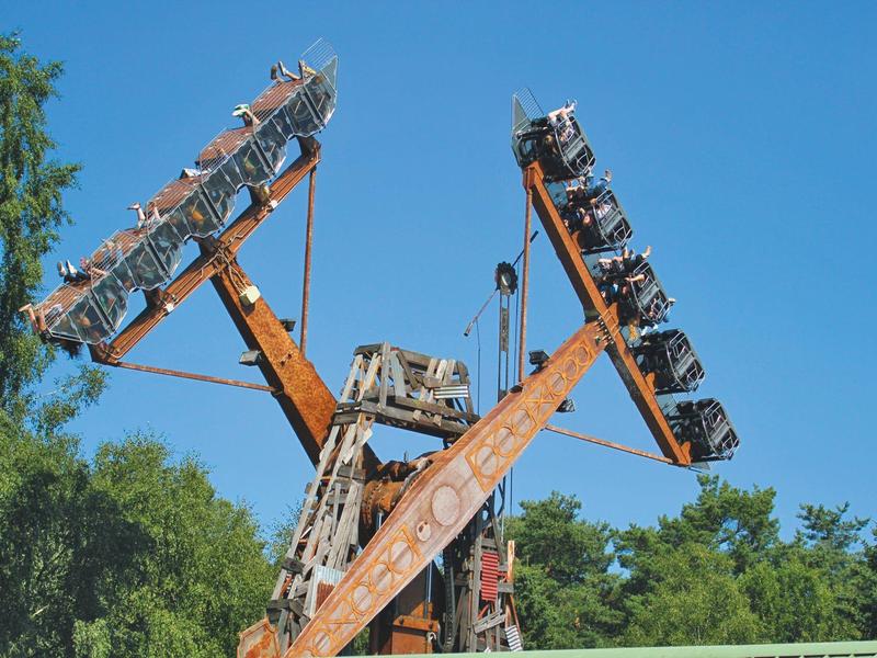 Veraltetes, rostiges Radargerät steht vor blauem Himmel und Bäumen.