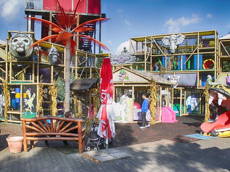 Buntes, kinderfreundliches Abenteuer-Spielgelände mit Rutsche, Schaukeln und Wasseraktivitäten.