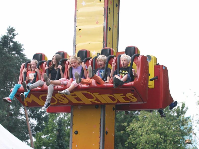 Sechs Personen auf einem Freizeitpark-Fahrgeschäft, das sie in die Luft hebt.