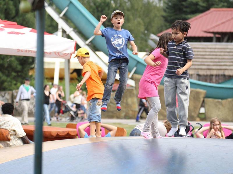 Kinder springen und spielen fröhlich auf einem Trampolin im Freien.