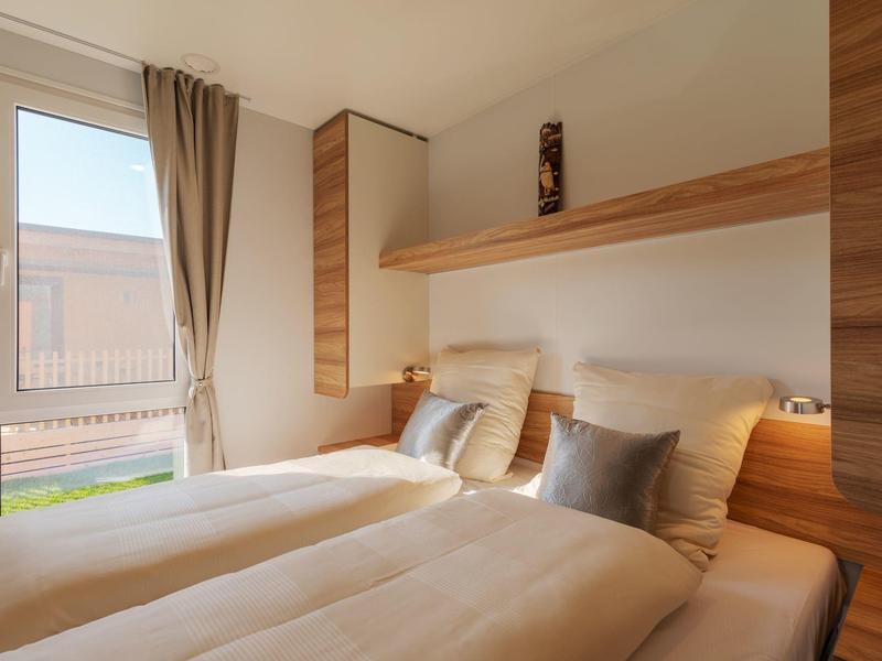 Modernes Zimmer mit zwei Einzelbetten, Holzakzenten und großem Fenster mit Blick nach draußen.