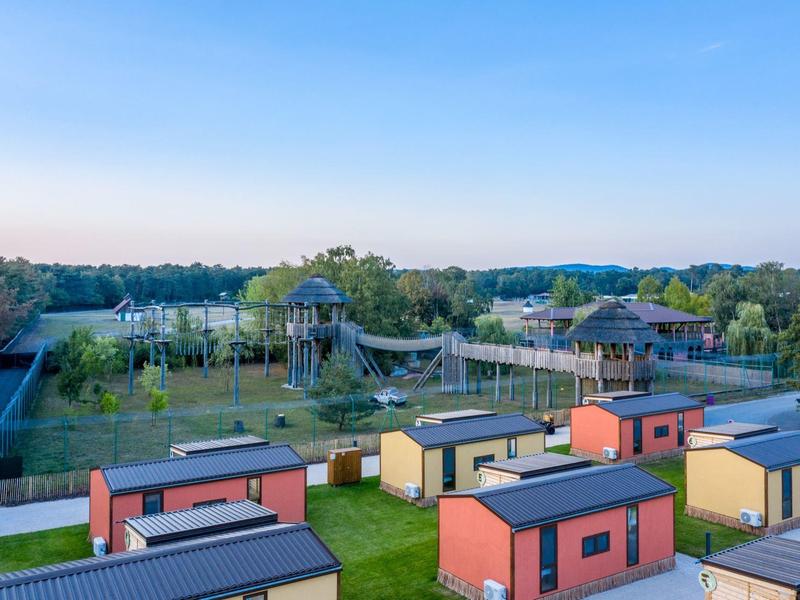 Ferienhäuser vor einem großen, grünen Spielplatz mit Klettergerüsten