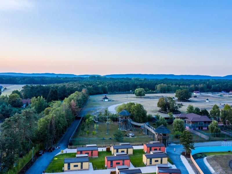 Blick auf eine hügelige Landschaft mit Bäumen und bunten Häusern bei klarem Himmel.