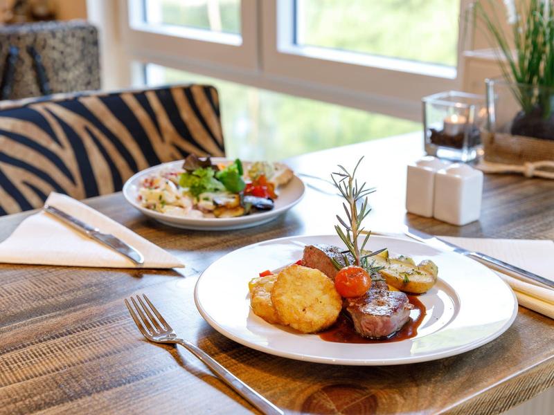 Elegantes Hotelrestaurant mit Holz-Esstisch, serviert feines Essen und Blick auf Fenster.