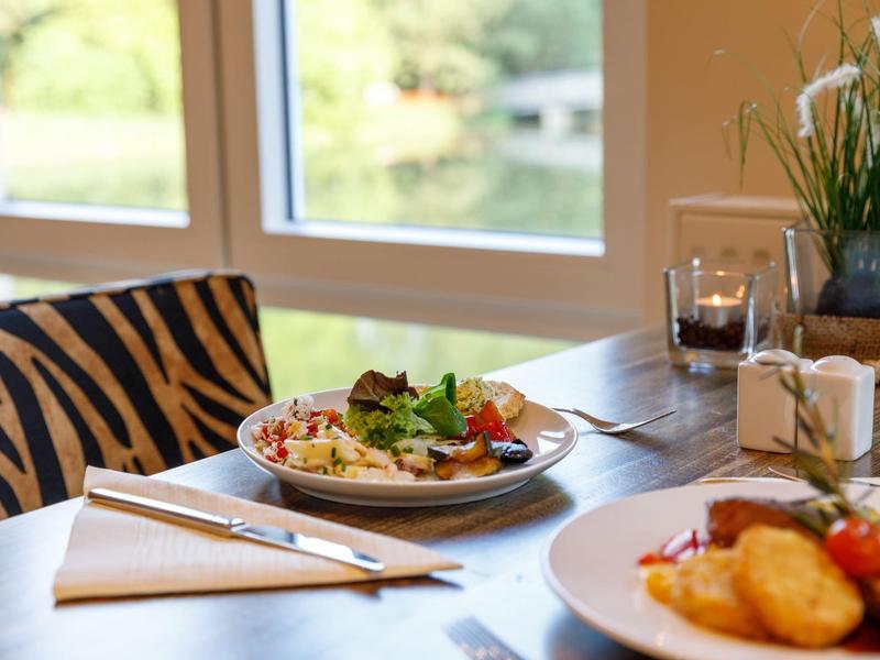 Gemütlicher Tisch am Fenster mit serviertem Essen und Zebra-Musterstuhl.