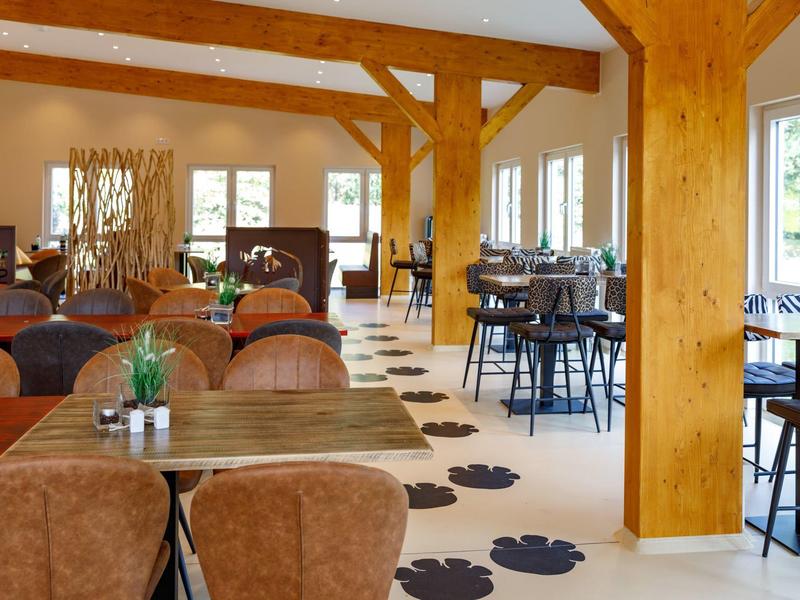 Helles Restaurant mit Holzbalken, bequemen Sesseln und einzigartigem pfotenförmigem Bodenmuster.
