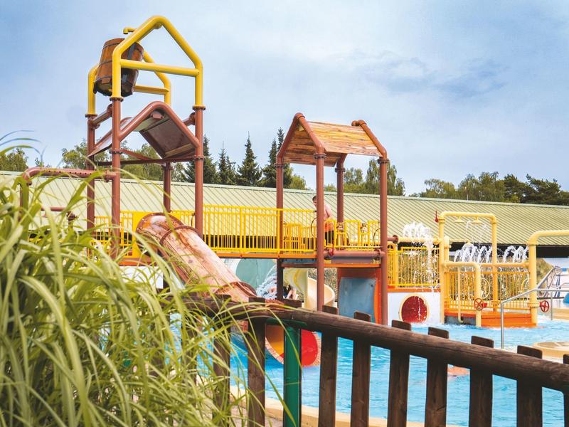 Bunter Wasserspielplatz mit Rutschen und Wasserbecken in einem Ferienressort.