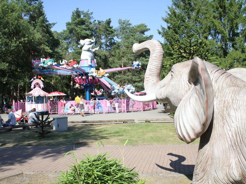 Ein Freizeitpark mit buntem Karussell und einem großen Elefanten-Skulptur im Vordergrund.
