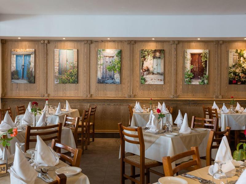 Ein elegantes Restaurant mit weiß gedeckten Tischen, Holzmöbeln und dekorativen Wandbildern.