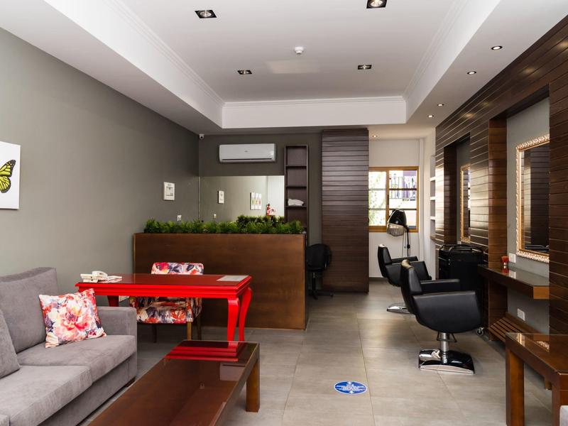 Moderner Friseursalon mit grauer Wand, rotem Tisch, Sofa und Holzverkleidung an der rechten Seite.