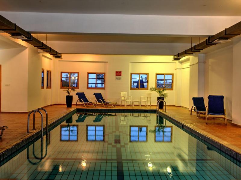 Innen-Schwimmbad mit rechteckigem Becken, blauer Wasserfläche und mehreren Liegestühlen an den Wänden.