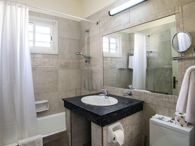 Kompaktes Badezimmer mit grauen Fliesen, weißer Badewanne, modernen Sanitäranlagen und schwarzer Arbeitsplatte.