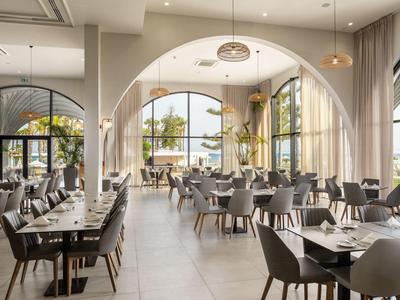 Helles Restaurant mit großen Rundbogenfenstern, modernen Möbeln und elegant gedeckten Tischen.