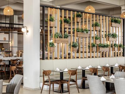 Modern hotelrestaurant met houten elementen, hangplanten en stijlvolle zitgedeeltes.