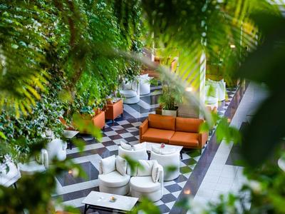 Een ontspannen buitenruimte met groene planten, comfortabele banken en een dambordvloer.