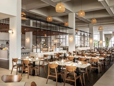 Moderne hotelrestaurant met houten tafels, stoelen en stijlvolle hanglampen.