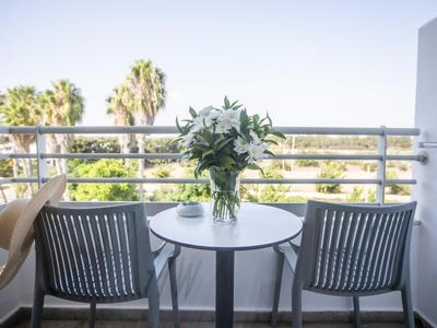 Balkon mit zwei Stühlen, rundem Tisch, Blumenstrauß und Sonnenschutzwand.