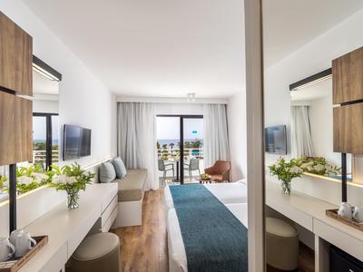 Modernes Hotelzimmer mit Doppelbett, Sitzbereich und Balkon mit Meerblick.