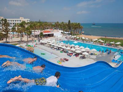 Hôtel avec plusieurs piscines, transats et vue sur la mer par une journée ensoleillée.