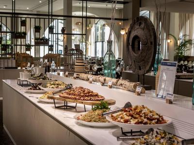 Buffet mit verschiedenen Vorspeisen und Snacks auf weißen Tellern in modernem Restaurant.