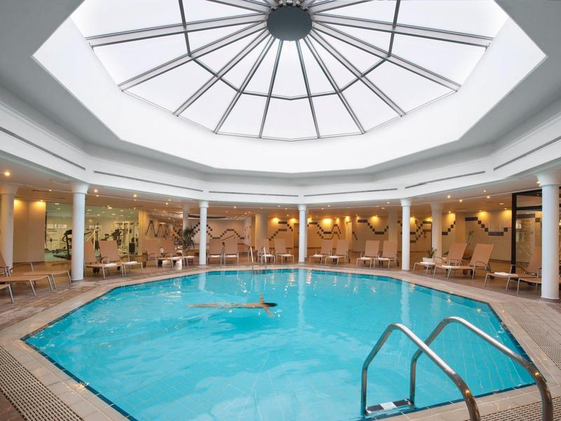 Innenraum eines runden Schwimmbads mit Glaskuppel und Wänden in hellem Beige.