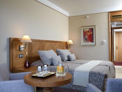 Modernes Hotelzimmer mit Doppelbett, Nachttischlampen und einem Tisch mit Getränken.