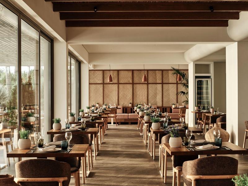 Hell eingerichteter Hotelrestaurantbereich mit Holztischen und gedeckten Stühlen.