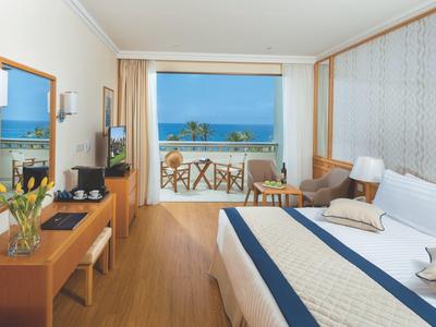 Gemütliches Hotelzimmer mit großem Bett, Holzmöbeln und Balkon mit Meerblick.