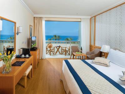 Camera d'hotel moderna con letto matrimoniale, mobili in legno e vista mare dal balcone.