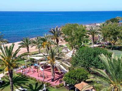 Vista di una spiaggia con palme e un mare blu sotto un cielo limpido.