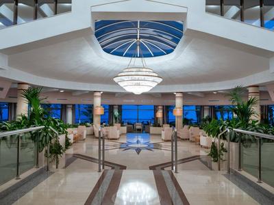 Elegante hall dell'hotel con illuminazione elegante e vista sul mare al crepuscolo.