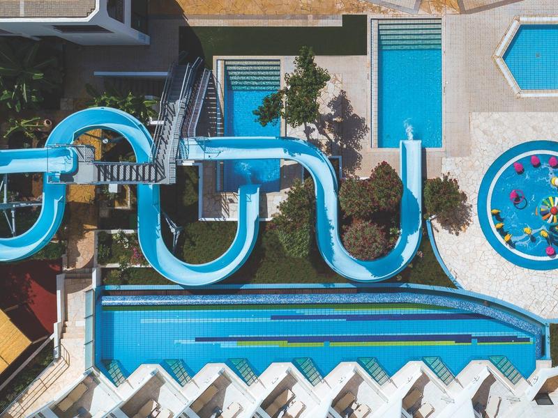 Wasserpark mit blauen Rutschen, Pool und bunter Wasserattraktion aus der Vogelperspektive.