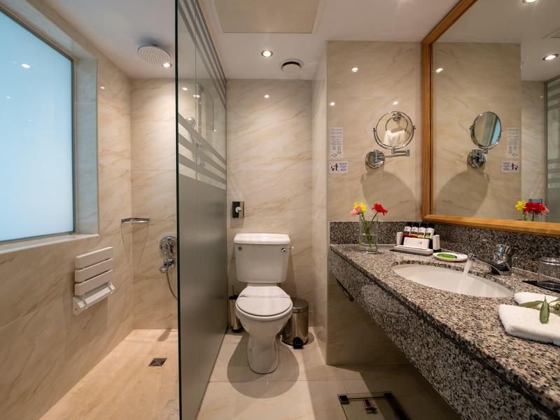 Moderne Bad mit Glasdusche, weißen Fliesen, Doppelwaschbecken und großem Spiegel.