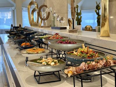 Moderne Küche mit langer Arbeitsfläche, mehreren bunten Gerichten auf schwarzen Gestellen.