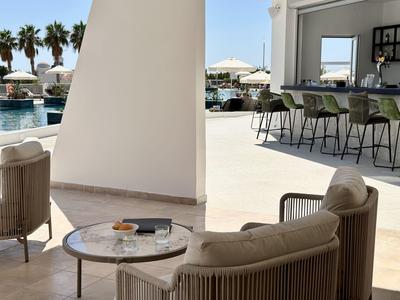 Moderne buitenlounge met zitplaatsen en uitzicht op zwembad en palmbomen.