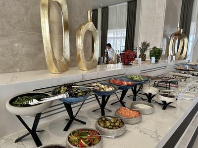 Buffet mit verschiedenen Vorspeisen auf weißer Marmorplatte und goldfarbenen Dekoobjekten.