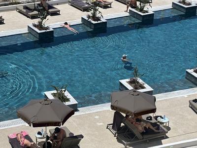 Moderne buitenzwembad met parasols en ligstoelen bij een hotel of resort.