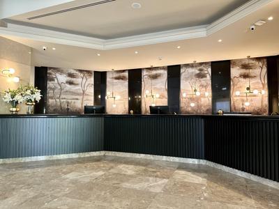 Moderne hotel lobby receptie met zwarte balie en stijlvolle verlichting.