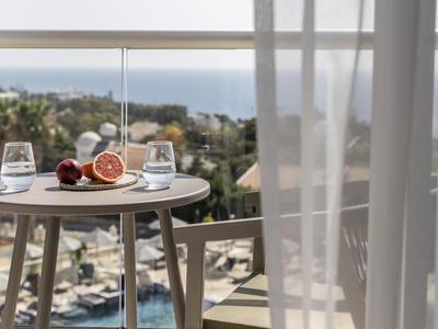 Blick vom Hotelzimmer mit Tisch, frischem Obst und Meer im Hintergrund.