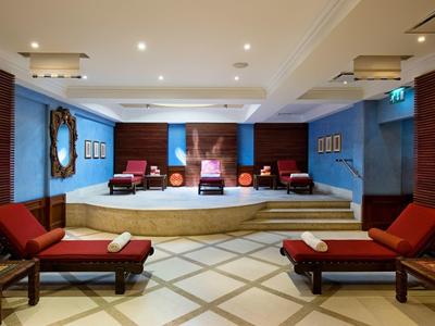 Eleganter Wellnessbereich mit roten Liegen, blauen Wänden und sanfter Beleuchtung.