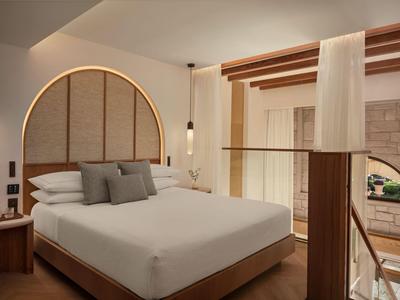 Nowoczesny pokój hotelowy z podwójnym łóżkiem, drewnianymi akcentami i ciepłym oświetleniem.