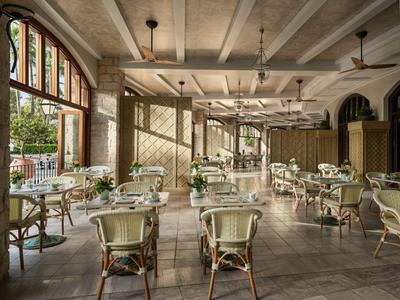Jasna, elegancka sala restauracyjna hotelu z wiklinowymi krzesłami i dużymi oknami wychodzącymi na taras.