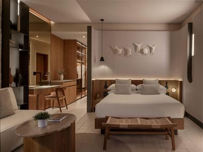 Nowoczesny pokój hotelowy z łóżkiem podwójnym, drewnianymi meblami i oświetleniem pośrednim.