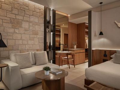 Nowoczesny pokój hotelowy z kamienną ścianą, przytulną sofą, łóżkiem i stylowym oświetleniem.